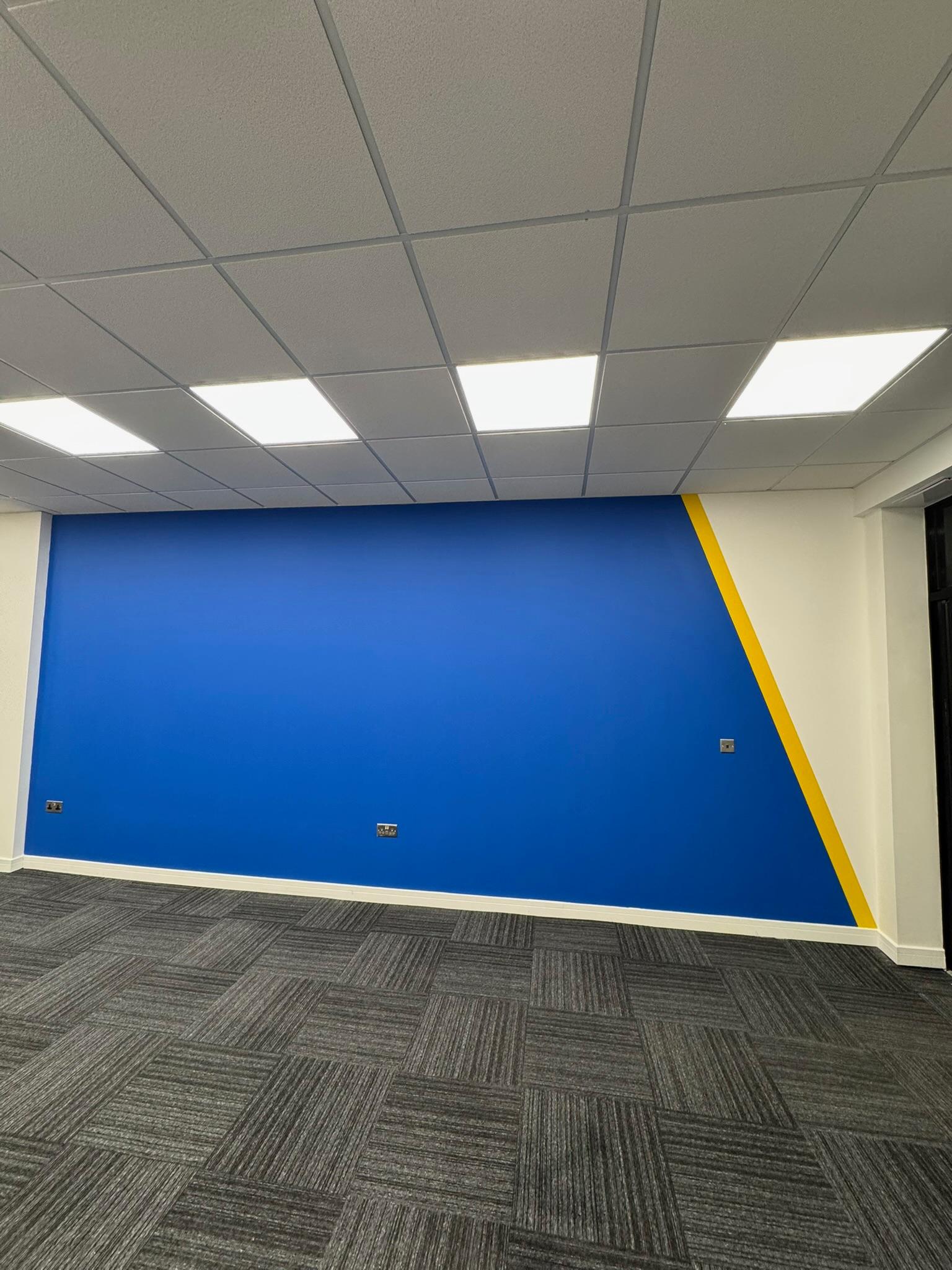 Green walls with bold blue botanical wallpaper feature