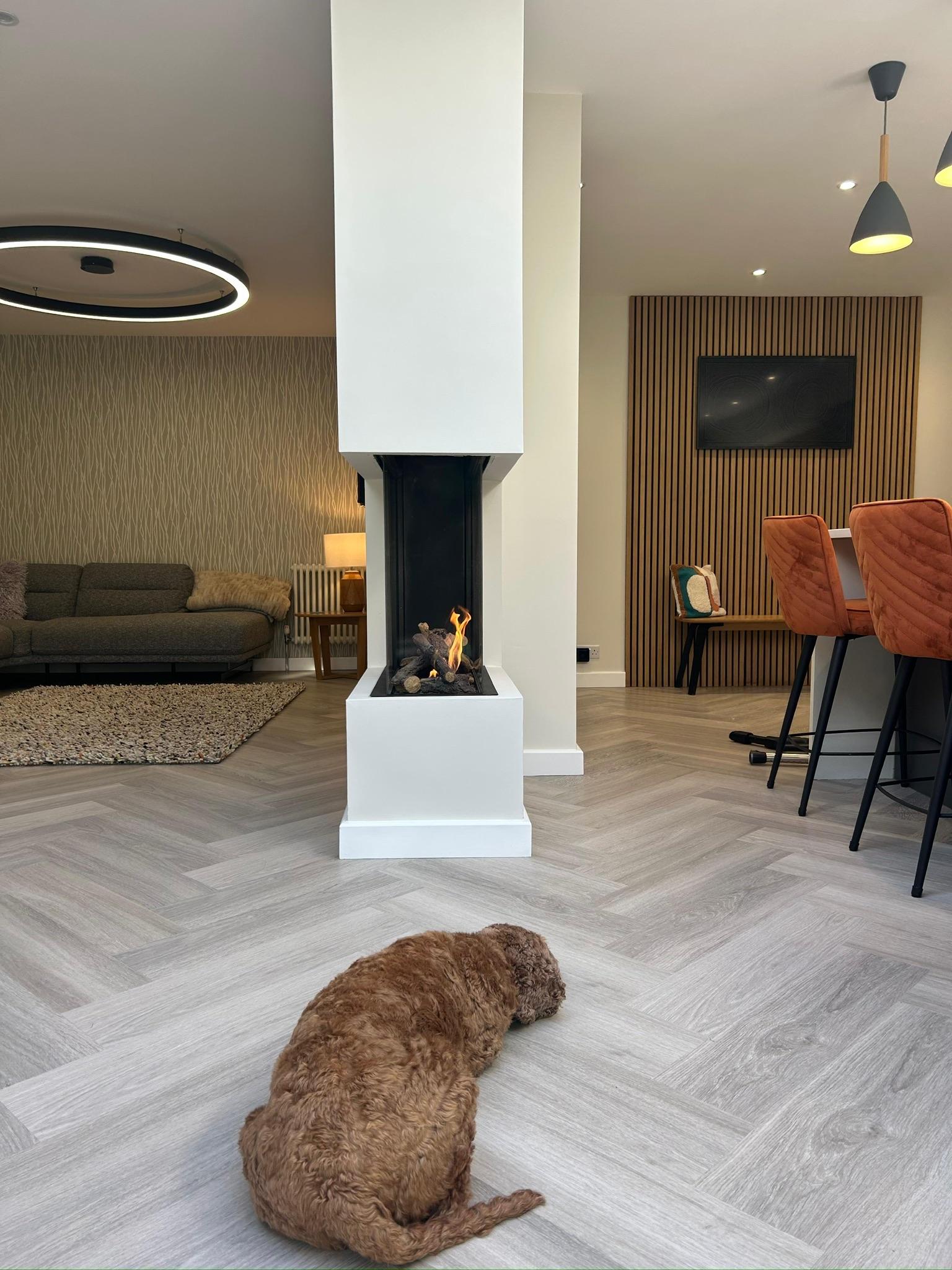 Open-plan living with central fireplace and herringbone flooring